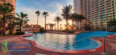 a large swimming pool with palm trees and buildings at Shores of Panama 1708 condo in Panama City Beach