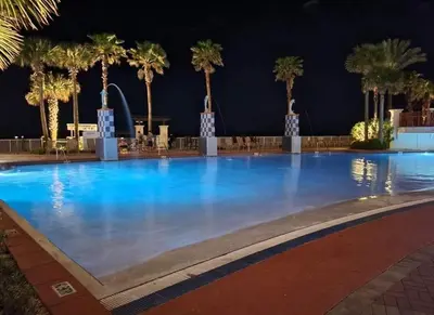 a large swimming pool with palm trees at night at Shores of Panama 1708 condo in Panama City Beach