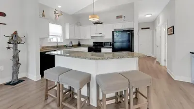 a kitchen with white cabinets and a island with bar stools at KK's Beach House - Newly remodeled, close to Seaside, easy walk to beach in Santa Rosa Beach