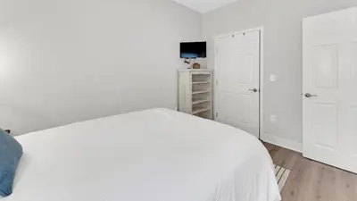 a white bedroom with a white bed and a tv at KK's Beach House - Newly remodeled, close to Seaside, easy walk to beach in Santa Rosa Beach