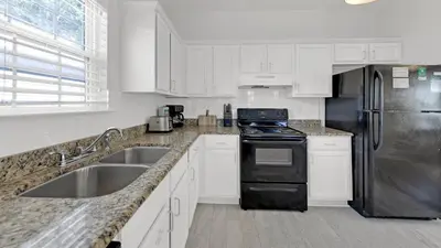a kitchen with white cabinets and a stainless steel refrigerator at Pelican House - Newly remodeled, professionally decorated, only about 1 mile to Seaside! in Santa Rosa Beach
