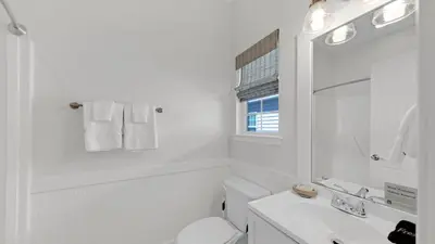 a white bathroom with a toilet and a sink at Pelican House - Newly remodeled, professionally decorated, only about 1 mile to Seaside! in Santa Rosa Beach
