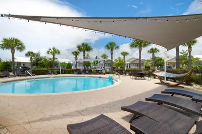 a swimming pool with chairs and a hammock at Pelican House - Newly remodeled, professionally decorated, only about 1 mile to Seaside! in Santa Rosa Beach
