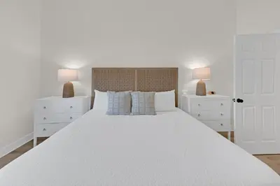 a white bedroom with a large white bed with two night stands at Emerald By Alma - Updated 3BD 2BA condo Seagrove Highlands in Santa Rosa Beach