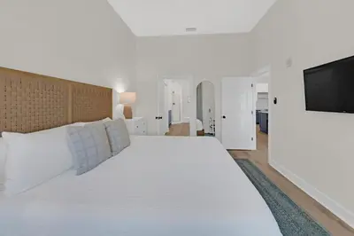 a white bedroom with a large bed and a flat screen tv at Emerald By Alma - Updated 3BD 2BA condo Seagrove Highlands in Santa Rosa Beach