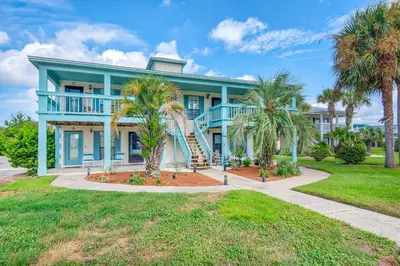 a blue house with palm trees in front of it at Seashells at the Beach Retreat in Panama City Beach