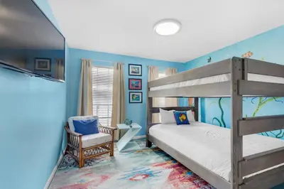 a bedroom with a bunk bed and a chair at Seashells at the Beach Retreat in Panama City Beach