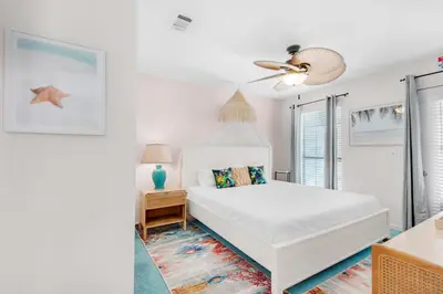 a white bedroom with a bed and a ceiling fan at Seashells at the Beach Retreat in Panama City Beach