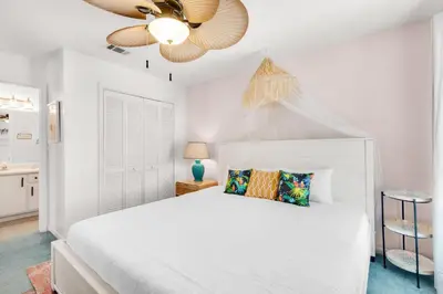a white bedroom with a bed and a ceiling fan at Seashells at the Beach Retreat in Panama City Beach