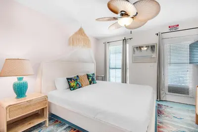 a bedroom with a white bed and a ceiling fan at Seashells at the Beach Retreat in Panama City Beach