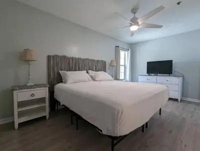 a bedroom with a bed with a ceiling fan and a television at Gulf Views from your 2 private balconies! in Panama City Beach