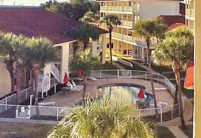 a view of a pool with palm trees and a building at Gulf Views from your 2 private balconies! in Panama City Beach