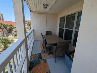 a porch with a wooden table and chairs on a balcony at Gulf Views from your 2 private balconies! in Panama City Beach