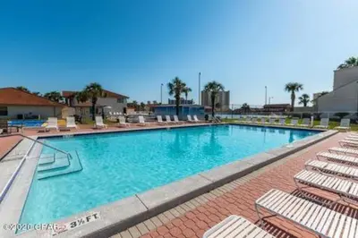 a large swimming pool with lounge chairs in a resort at Gulf Views from your 2 private balconies! in Panama City Beach