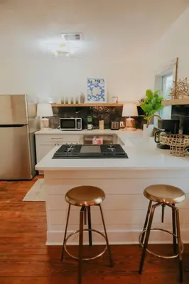a kitchen with a stove and two bar stools at Dream On – Style & Comfort Near Historic Downtown in Panama City