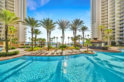 a swimming pool with palm trees and buildings at Shores of Panama 2122 in Panama City Beach