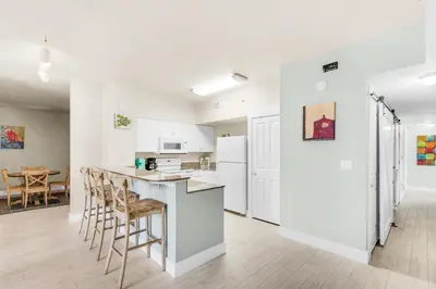 a kitchen with white cabinets and a bar with stools at Shores of Panama 2122 in Panama City Beach