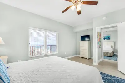 a white bedroom with a bed and a ceiling fan at Shores of Panama 2122 in Panama City Beach
