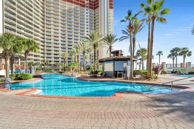 a swimming pool with palm trees and a large building at Shores of Panama 2122 in Panama City Beach
