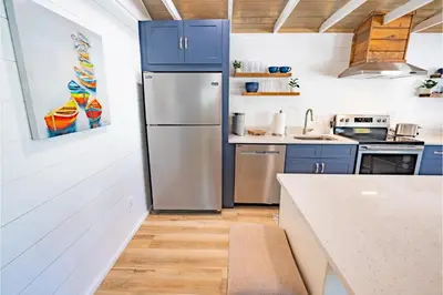 a kitchen with blue cabinets and a stainless steel refrigerator at Conch Cottage in Panama City Beach