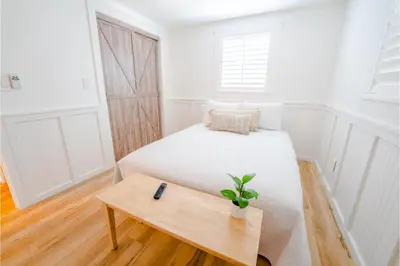 a white bedroom with a bed and a table at Conch Cottage in Panama City Beach