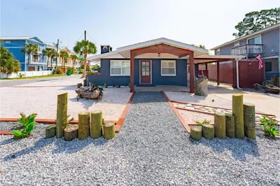 a house with a yard with wooden posts in front of it at Conch Cottage in Panama City Beach