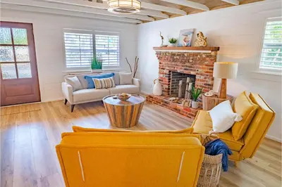 a living room with yellow furniture and a fireplace at Conch Cottage in Panama City Beach