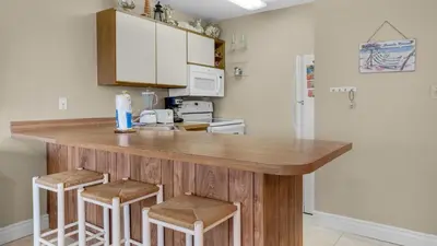 a kitchen with a wooden counter and stools at Hidden Beach 235 in Santa Rosa Beach
