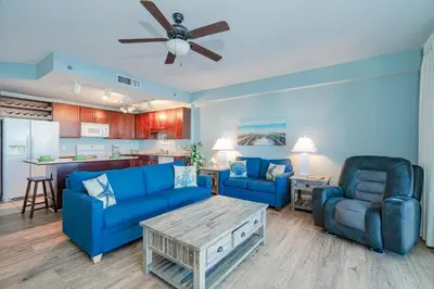 a living room with two blue couches and a kitchen at Laketown Wharf #119 by Nautical Properties in Panama City Beach