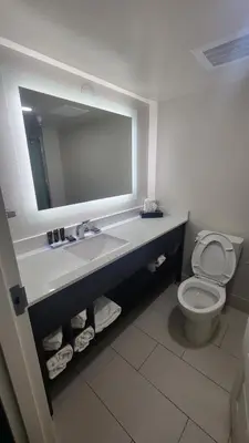 a bathroom with a sink and a toilet with a mirror at Wingate by Wyndham Panama City Area Lynn Haven in Panama City