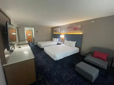 a hotel room with two beds and a chair at Wingate by Wyndham Panama City Area Lynn Haven in Panama City