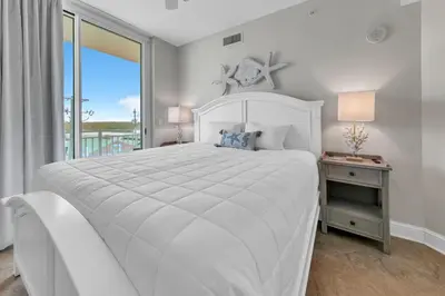 a white bedroom with a large bed and a window at Aqua Resort 401 - Piece of Serenity in Panama City Beach