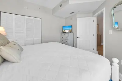 a white bedroom with a white bed and a television at Aqua Resort 401 - Piece of Serenity in Panama City Beach