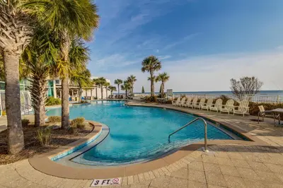 a swimming pool with palm trees and chairs at Aqua Resort 401 - Piece of Serenity in Panama City Beach