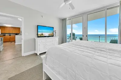 a white bedroom with a large bed and a television at Aqua Resort 401 - Piece of Serenity in Panama City Beach