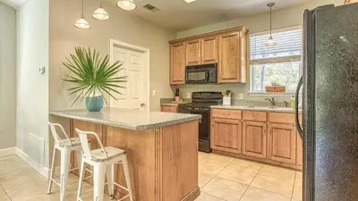 a kitchen with wooden cabinets and a island with stools at Flip Flop Cottage - Great rates and dog friendly with additional pet fee in Santa Rosa Beach