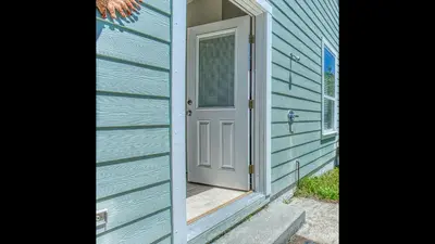 a door on a blue house with a porch at Flip Flop Cottage - Great rates and dog friendly with additional pet fee in Santa Rosa Beach