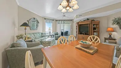 a dining room and living room with a wooden table at Dunes of Seagrove 301B - Updated decor with Great views and Beach service included March through October in Santa Rosa Beach