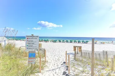 a beach with a sign in the sand and the ocean at Dunes of Seagrove 301B - Updated decor with Great views and Beach service included March through October in Santa Rosa Beach