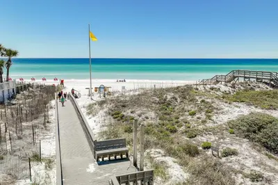 a boardwalk to a beach with a bench and the ocean at Beachside Villas #312 in Santa Rosa Beach