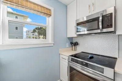 a kitchen with white cabinets and a window at Beachside Villas #312 in Santa Rosa Beach