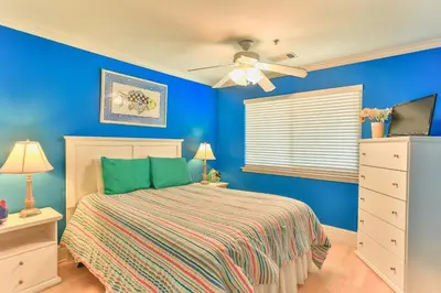 a blue bedroom with a bed and a ceiling fan at Commodore's Retreat 402 - Beach service included 2 chairs and 1 umbrella March through October in Santa Rosa Beach