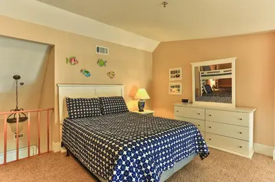 a bedroom with a bed and a dresser and a mirror at Commodore's Retreat 402 - Beach service included 2 chairs and 1 umbrella March through October in Santa Rosa Beach