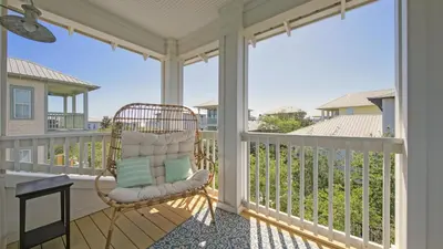 a rocking chair on a porch with a view of the ocean at Top of the Dunes - Recently Redecorated Short walk to the Beach in Santa Rosa Beach