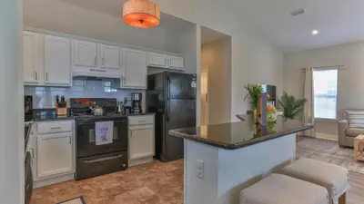 a kitchen with white cabinets and a black refrigerator at Elsie's Cove - Close to the Beach in Seagrove along 30A in Santa Rosa Beach