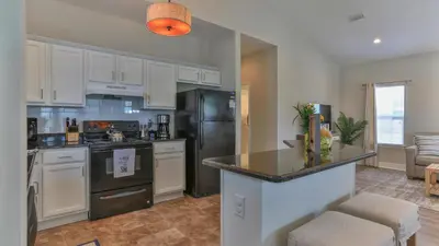 a kitchen with white cabinets and a black refrigerator at Elsie's Cove - Close to the Beach in Seagrove along 30A in Santa Rosa Beach
