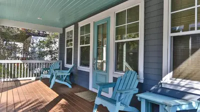 a porch with two blue chairs and a bench at Family Ties - Located in Seacrest Beach 2 Master bedrooms and a large communal pool in Rosemary Beach