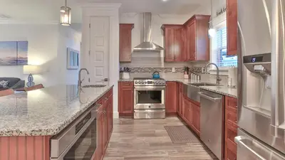a kitchen with wooden cabinets and stainless steel appliances at Hook, Wine, and Sinker - 3 plus Bedrooms Gulf views on 30A sleeps 12 with a hot tub in Santa Rosa Beach