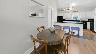 a kitchen with a wooden table and chairs and a kitchen with white cabinets at Once Upon a Tide - Close to Seaside on 30A and 3 blocks to beach in Santa Rosa Beach