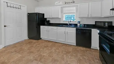 a kitchen with white cabinets and a black refrigerator at Once Upon a Tide - Close to Seaside on 30A and 3 blocks to beach in Santa Rosa Beach